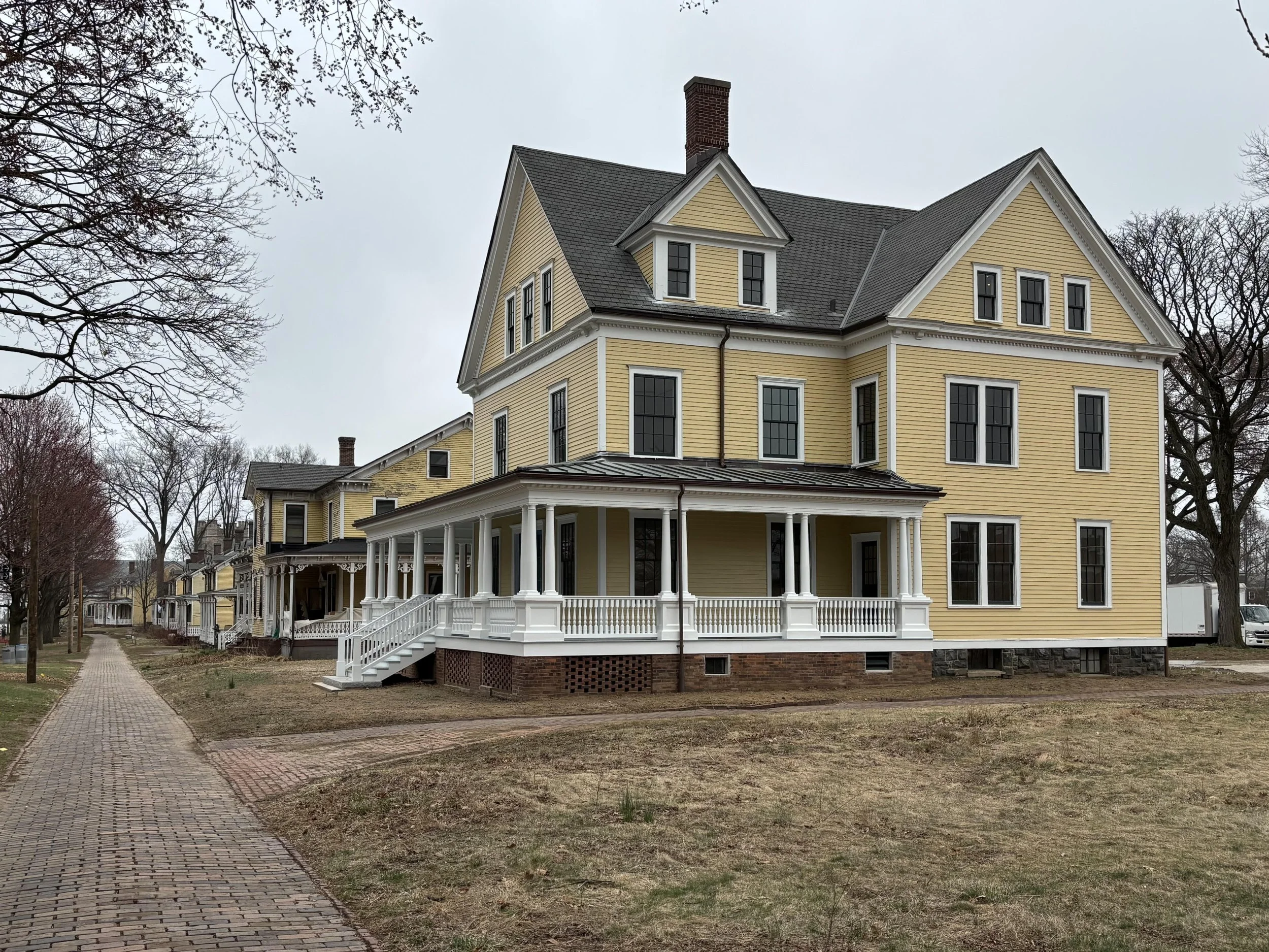 Restored yellow Victorian house with wraparound porch in Nolan Park on Governors Island