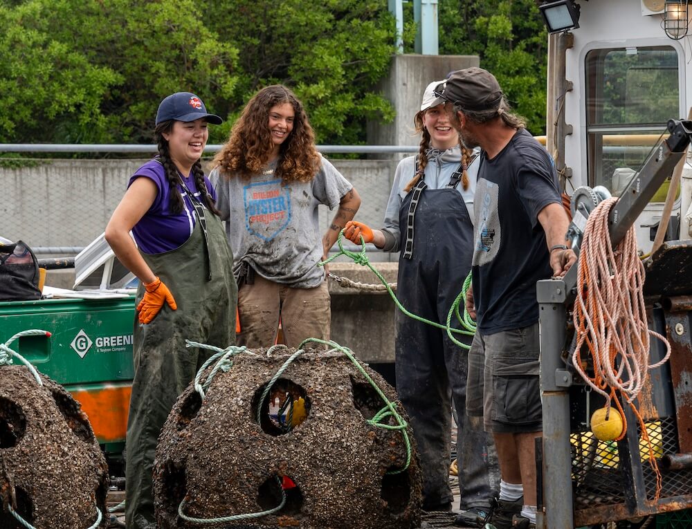 Crew sharing a laugh beside encrusted reef balls hauled onto the dock
