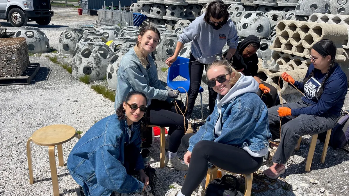 Volunteers tying rope among rows of concrete reef balls at an assembly event