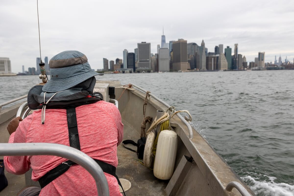 Crew member at the bow of a workboat crossing New York Harbor toward Lower Manhattan