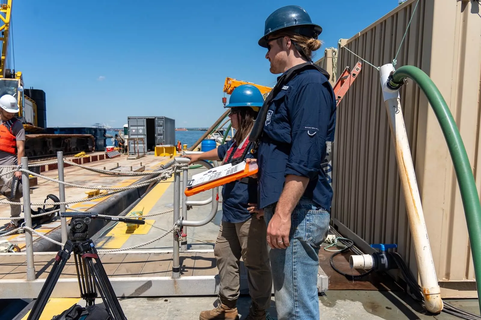 Two crew members in hard hats review a checklist aboard a construction barge