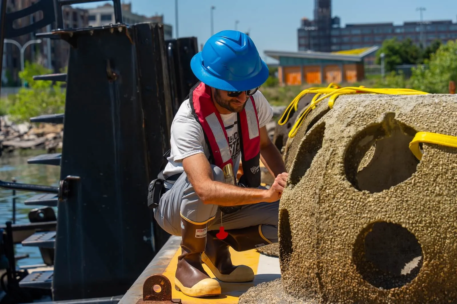 Worker in a hard hat rigging a concrete reef ball with straps for installation