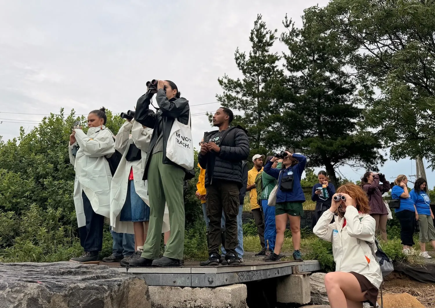 Visitors with binoculars scan the water's edge during a guided bird walk