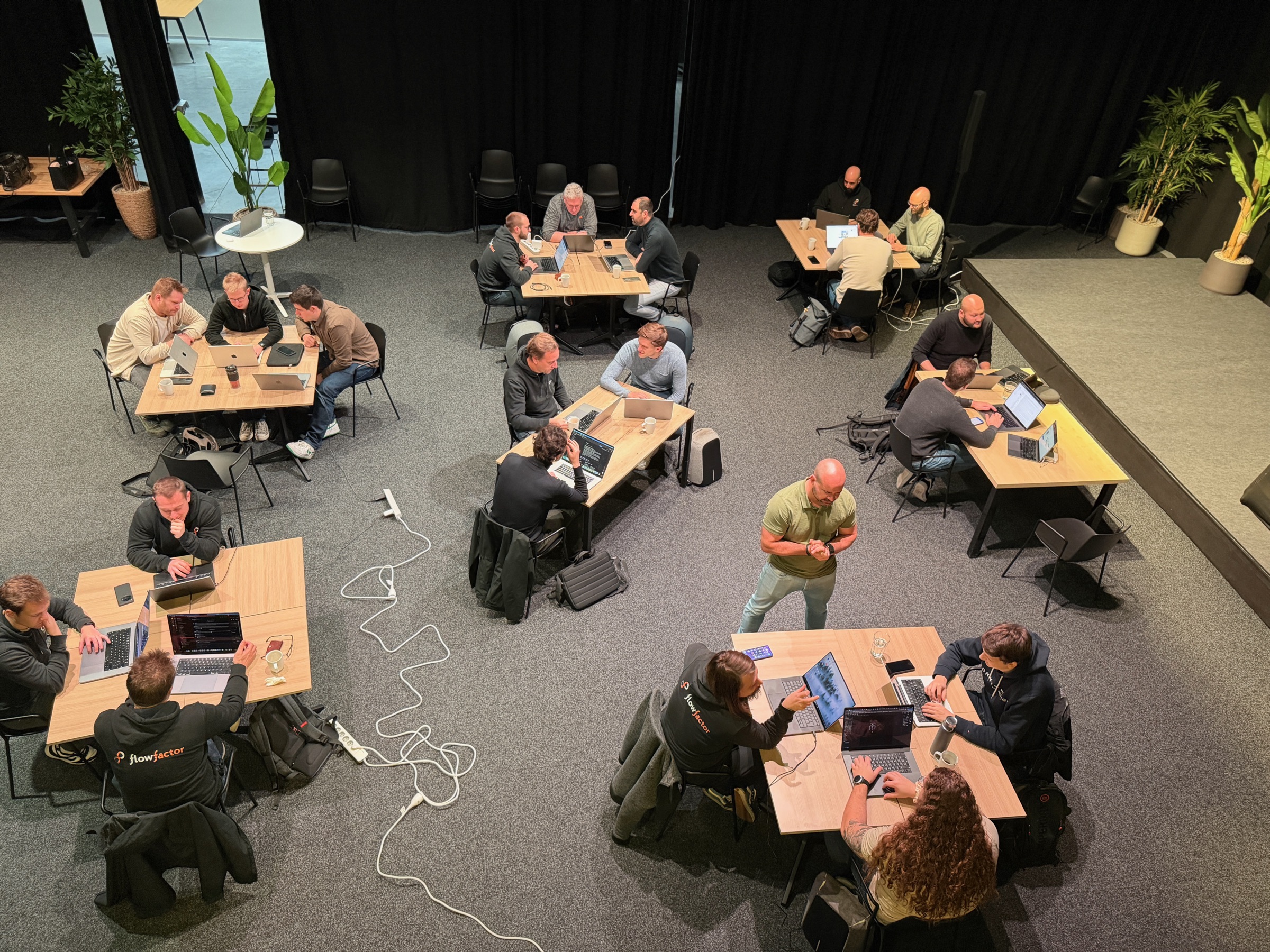 FlowFactor engineers working in small groups at laptops during a knowledge-sharing day