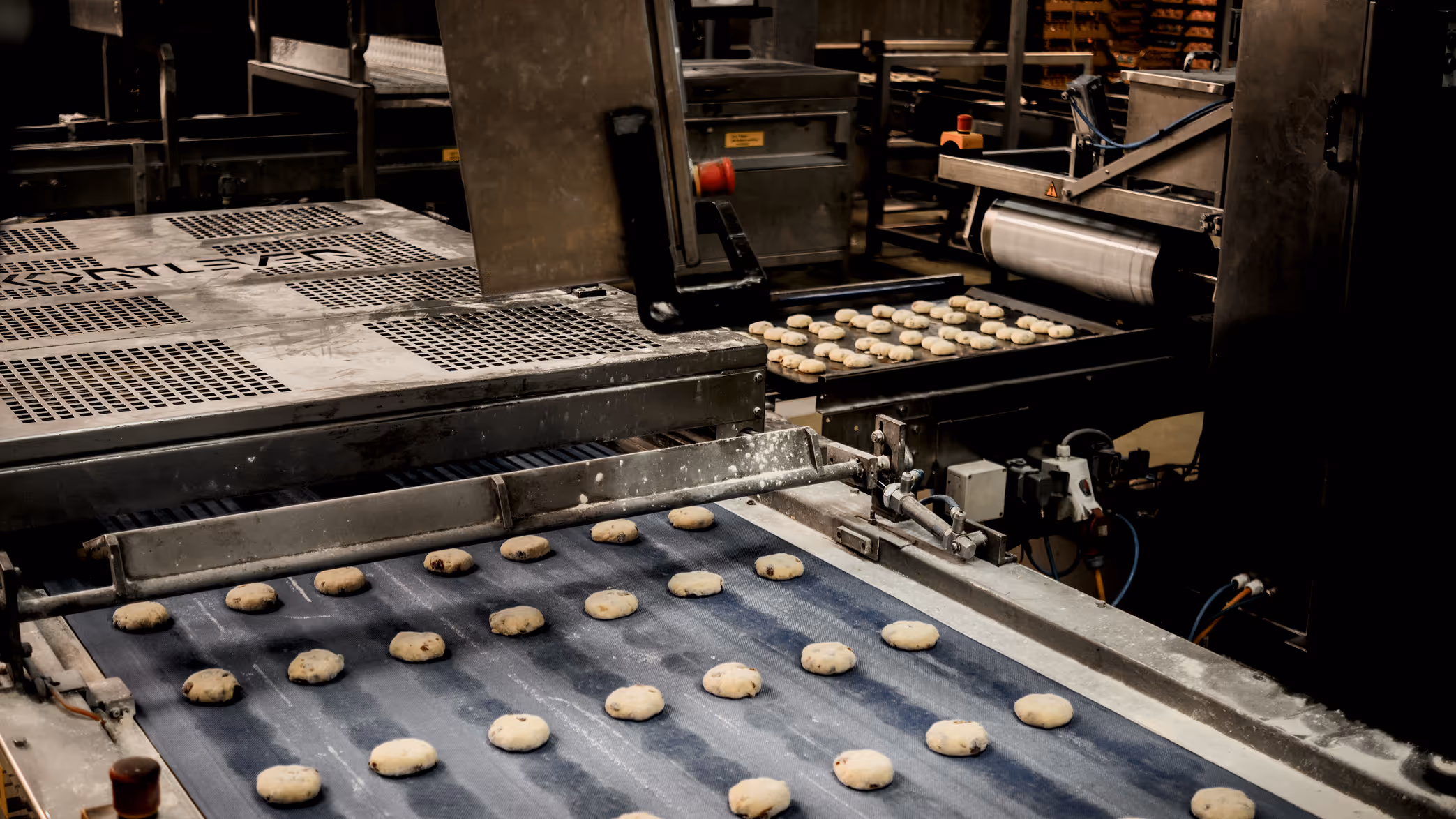Bakkersfabriek met koekjes die op een transportband worden geproduceerd en verplaatst door machines.
