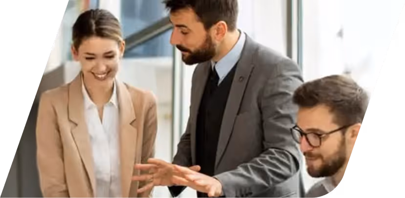 Three colleagues talking and smiling in a bright office, dressed in professional outfits.