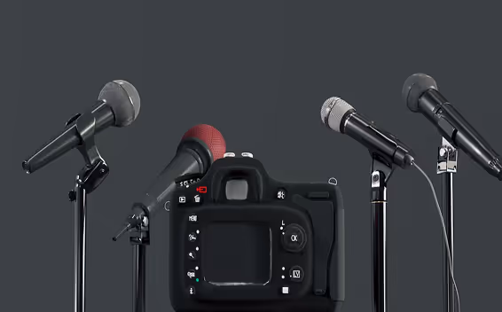 Un appareil photo noir entouré de quatre microphones sur fond gris foncé.