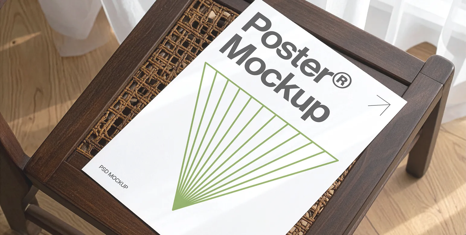 White poster mockup with green geometric fan-like design on a dark wooden chair with woven seat under natural light.