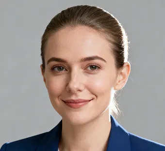 Portrait of a smiling woman with light skin, brown hair tied back, and blue blazer against a gray background.