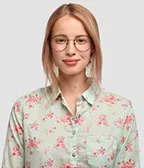 Young woman with glasses and pink floral shirt smiling against a gray background.