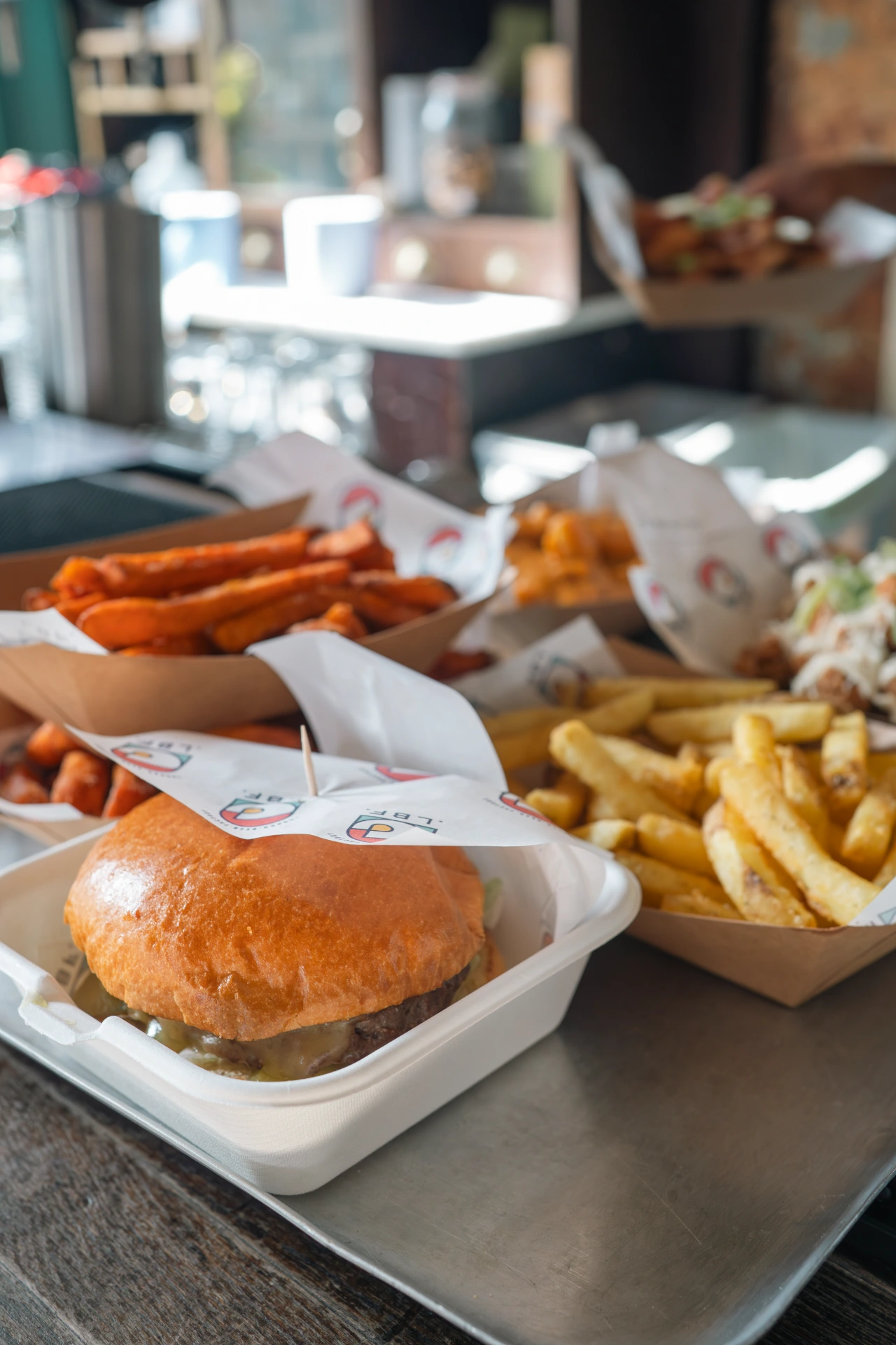 Smiling bartender with glasses shaking a cocktail shaker behind a bar with warm lighting and bottles in the background.