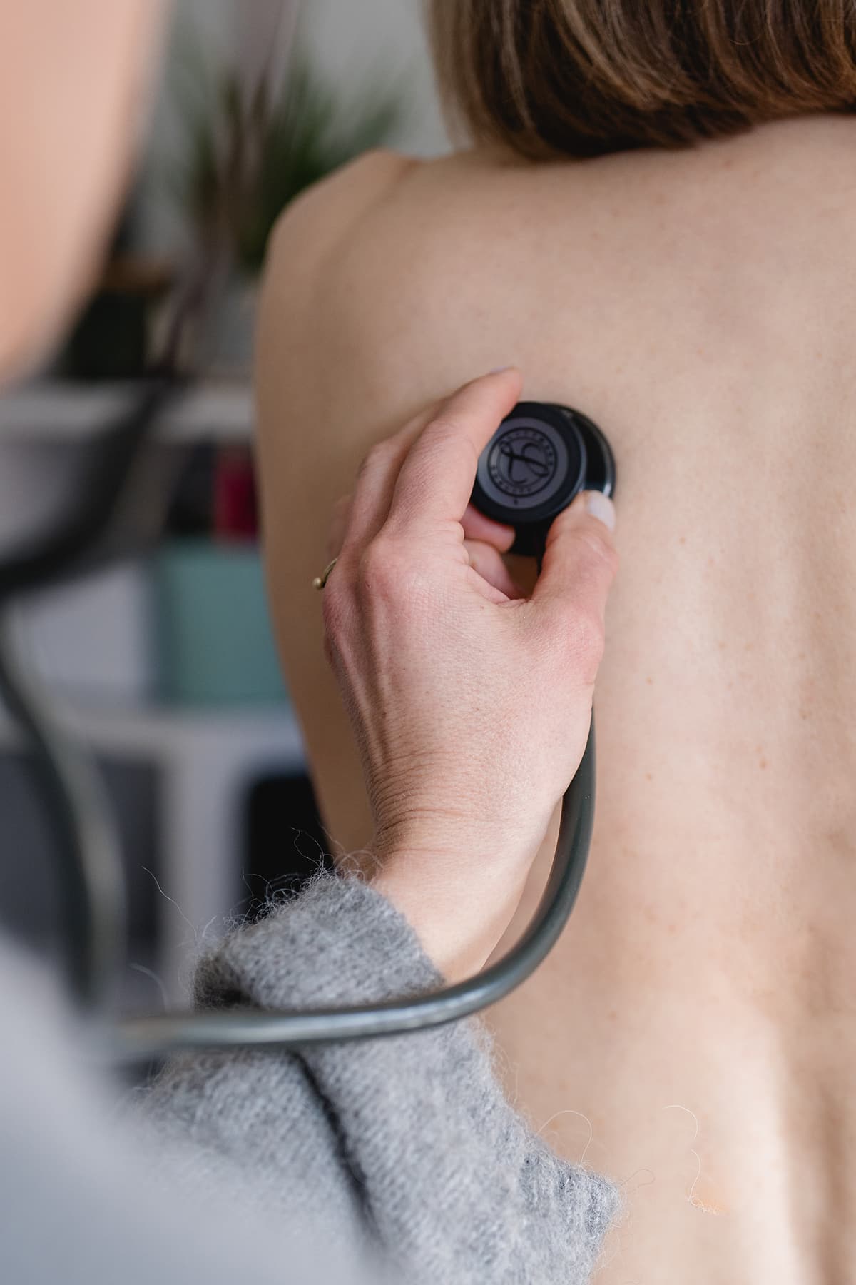 Dr. Rösch untersucht mit einem Stethoskop den Rücken einer Patientin