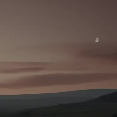 The moon is setting over the hills in the distance.