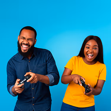 Man and woman smiling and playing video games with controllers against a blue background.