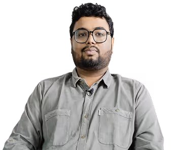 Man with glasses and beard wearing a gray button-up shirt against a black background.