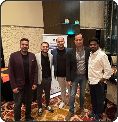 Five men standing together indoors on a patterned carpet in front of a banner.