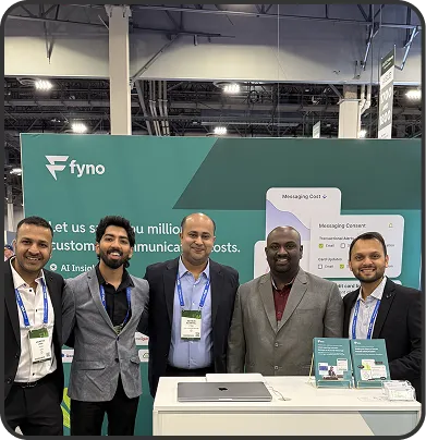 Five men in business attire standing behind a trade show booth with a green backdrop displaying the Fyno logo and product information.