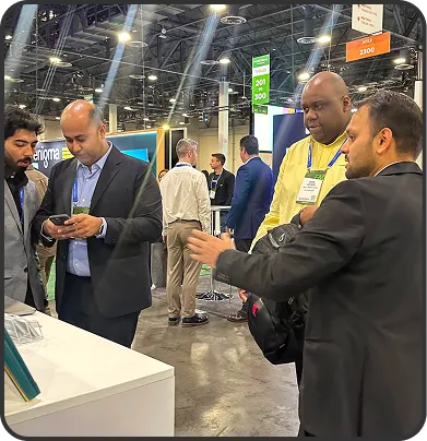 Four men engaged in conversation at a technology conference booth inside an exhibition hall.
