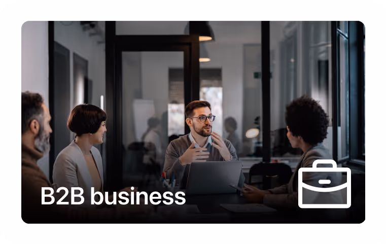 Four professionals engaged in a business meeting around a table with a laptop in a modern office.
