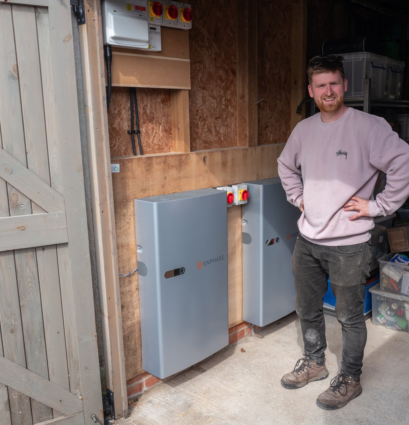 JellyWatt installer with two Enphase home batteries fitted in a garage
