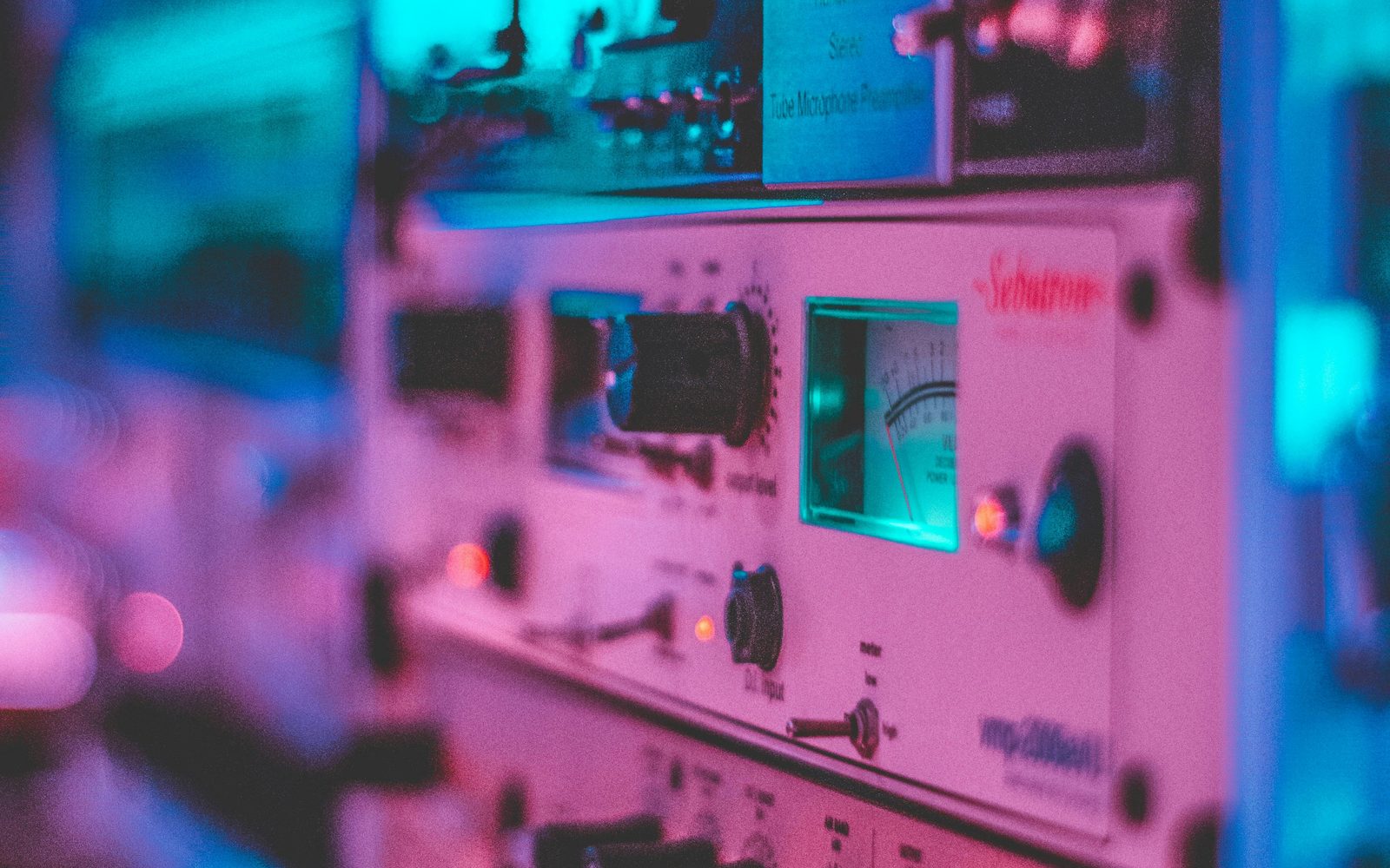 Studio audio equipment rack with neon lighting and analog meters.