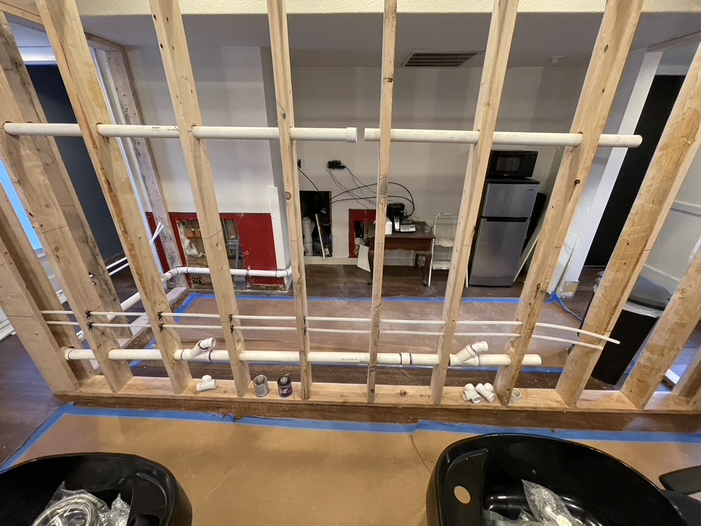 Exposed plumbing system installation in progress behind a newly framed wall