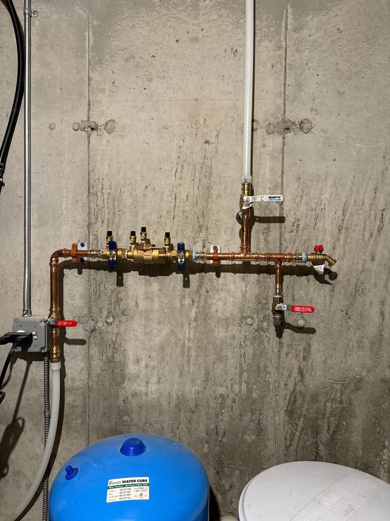 Main water line installation featuring copper piping and pressure tank