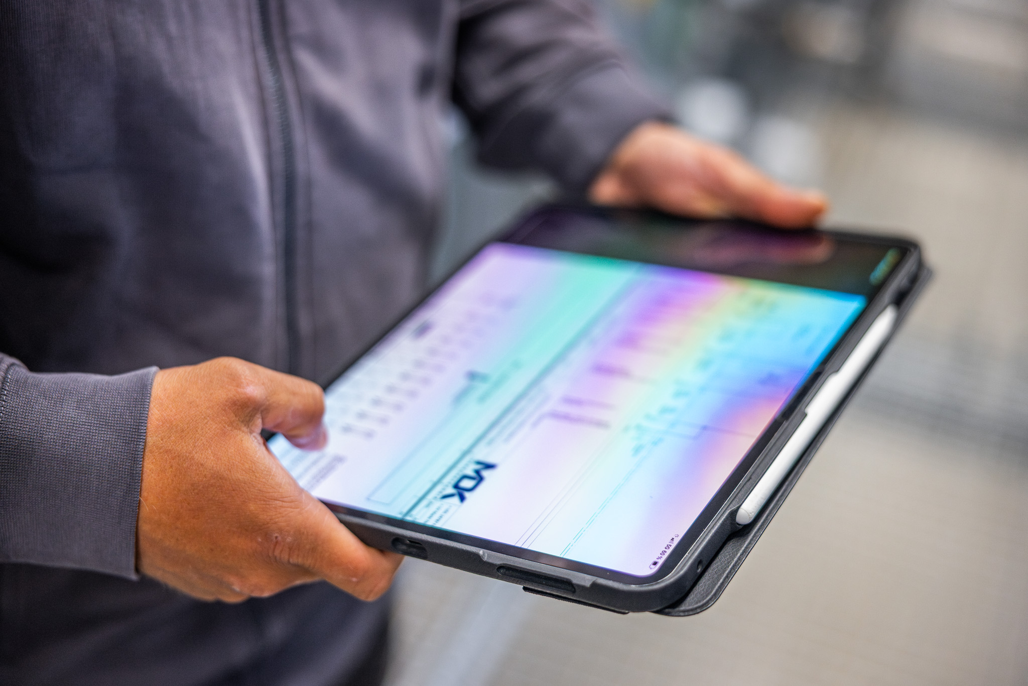 Person holding a tablet displaying a colorful digital interface with text and graphics.