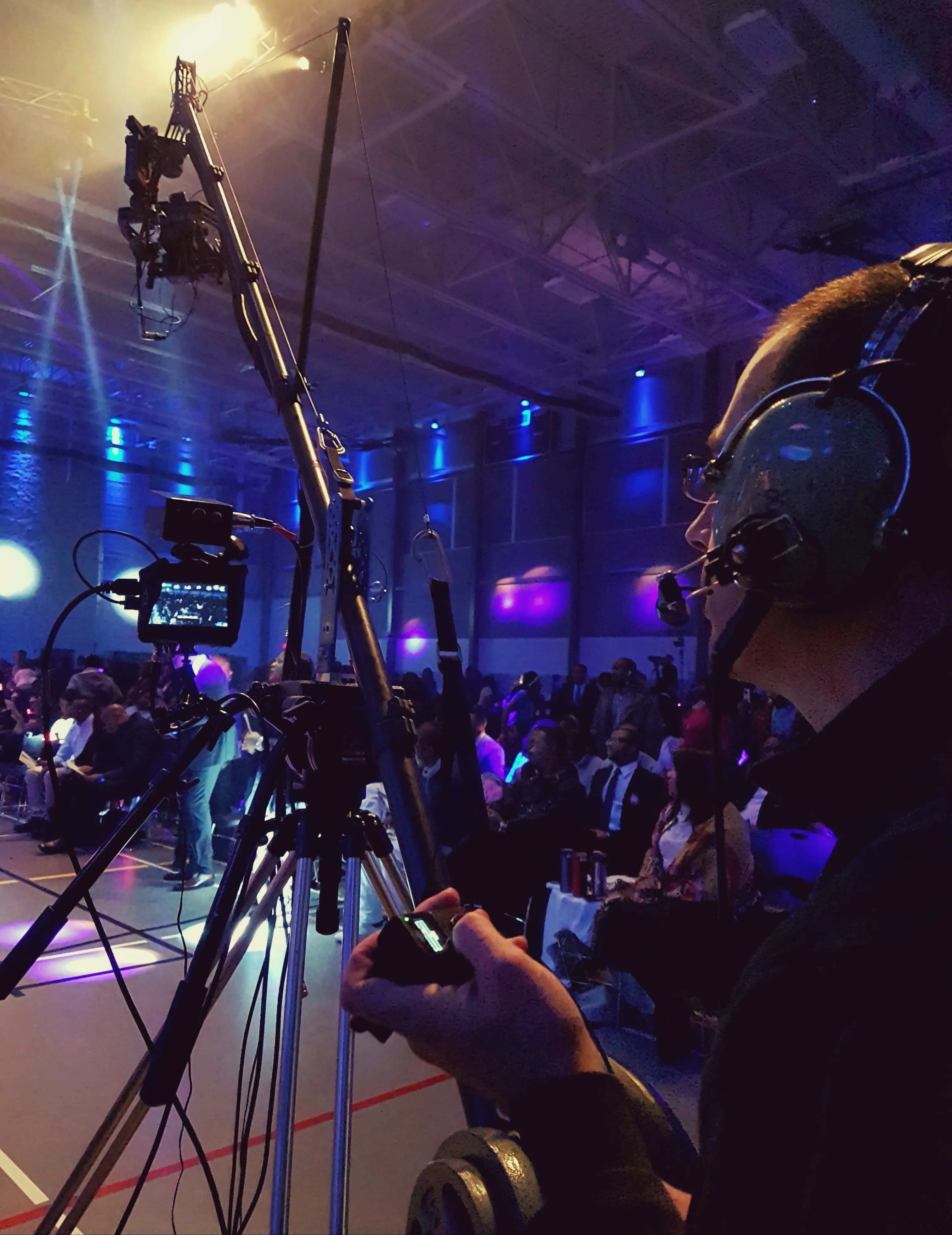 camera operator using a large camera on a crane in blue lights