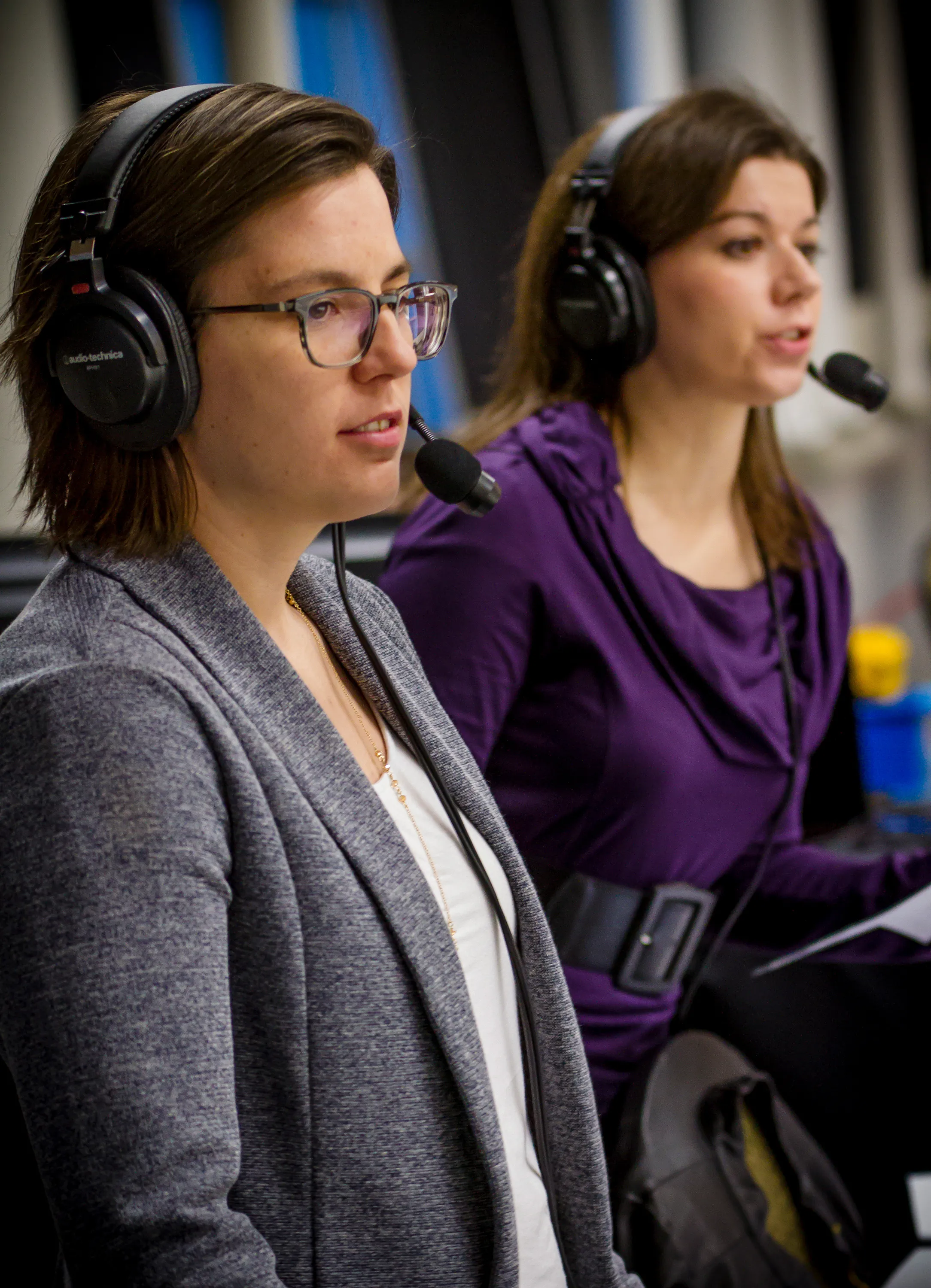two female sports commentators watching the hockey game wearing headsets