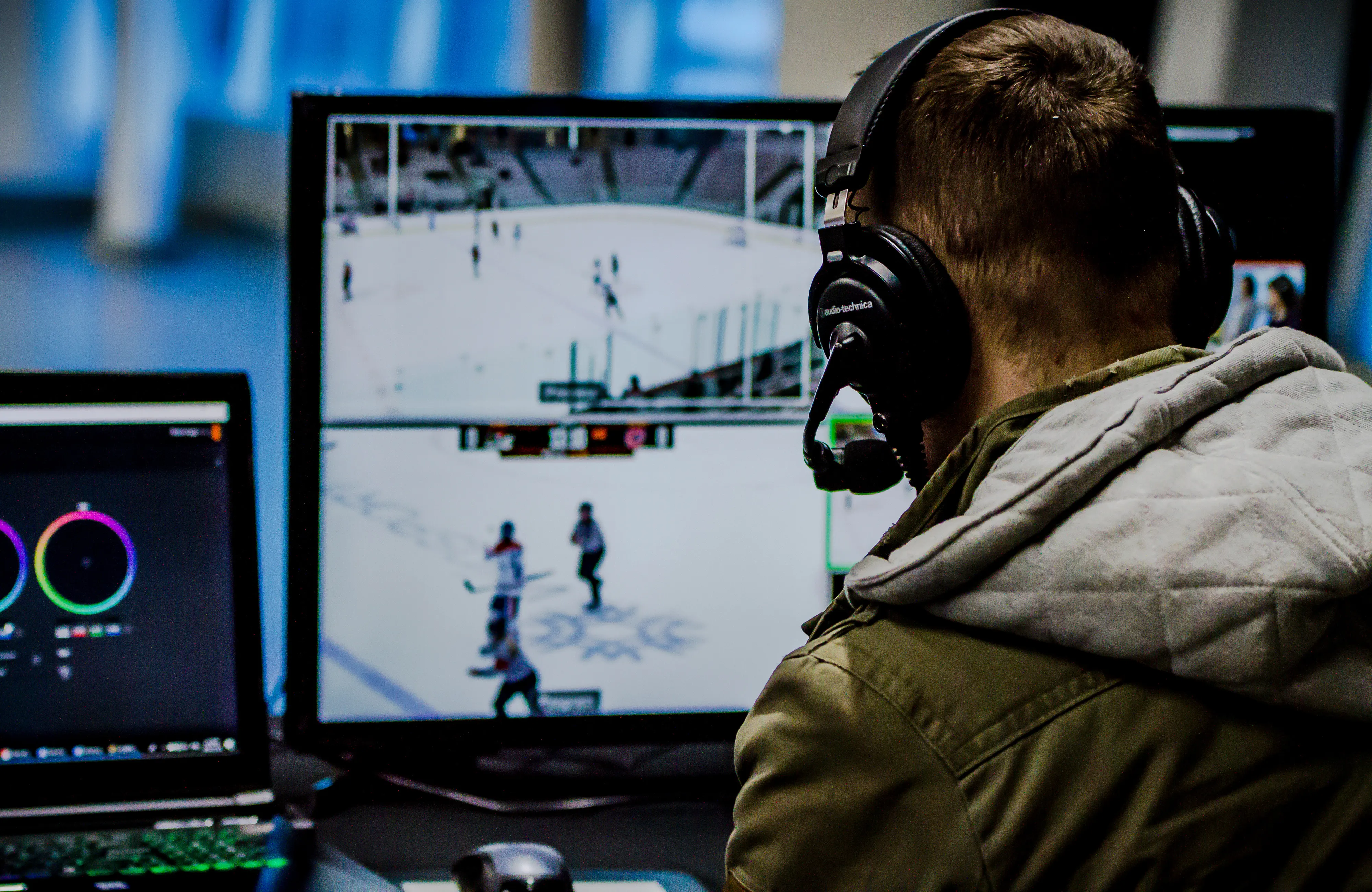 a man wearing headphones watches multiple screens of the broadcast of the hockey games