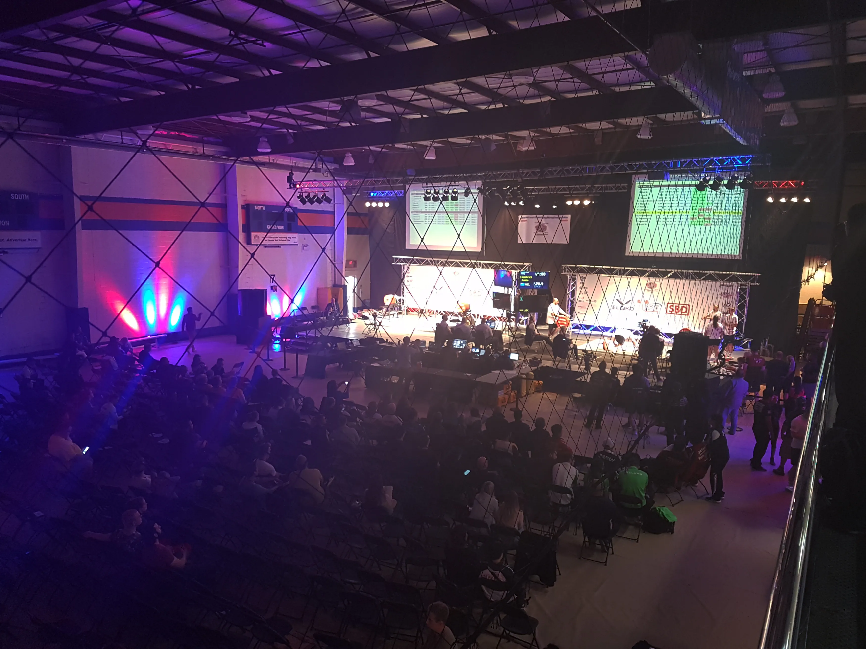 a wide shot of the set up of the stage and audience together with purple lights