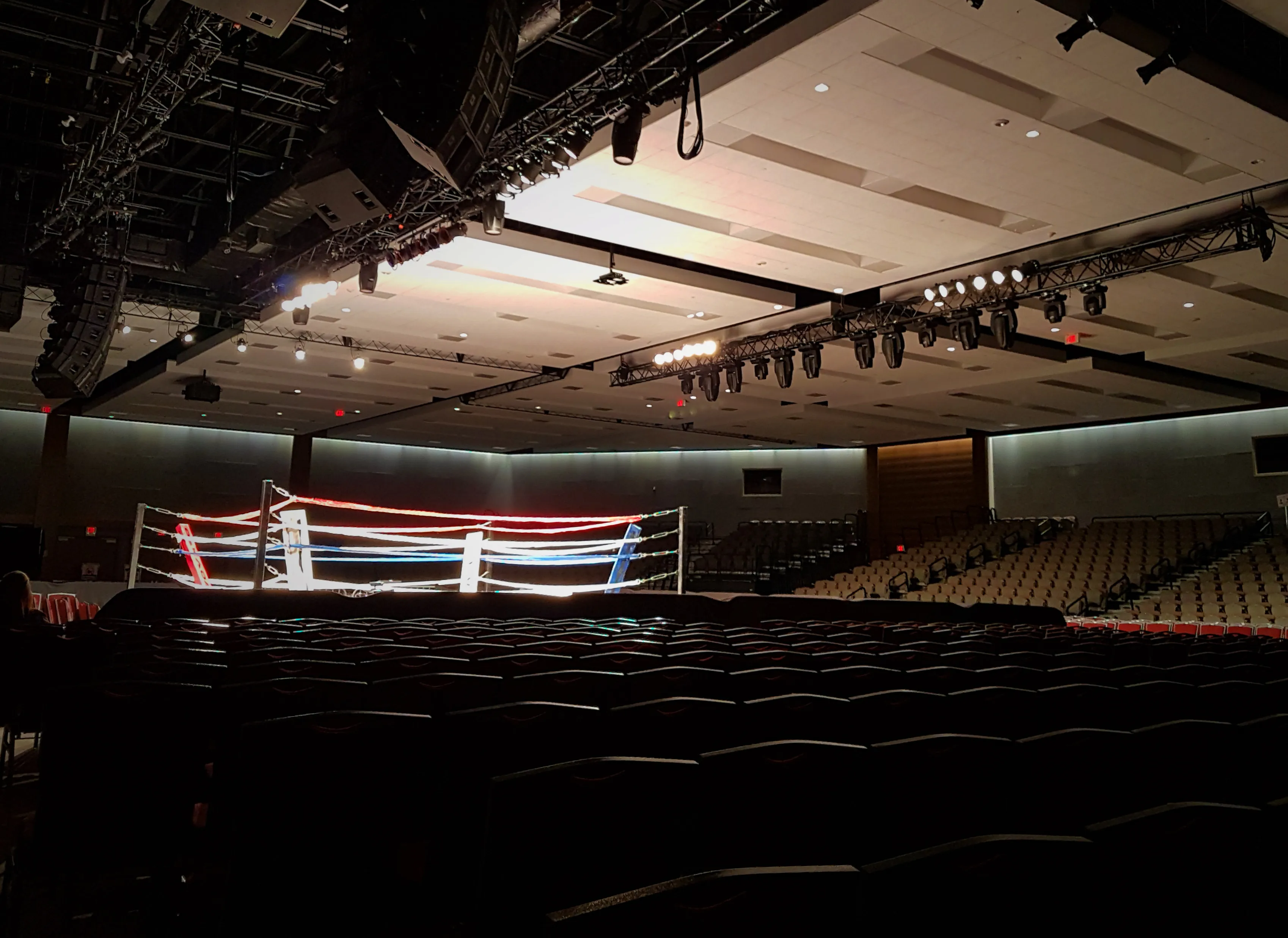 an empty arena with the boxing ring lit up in the center