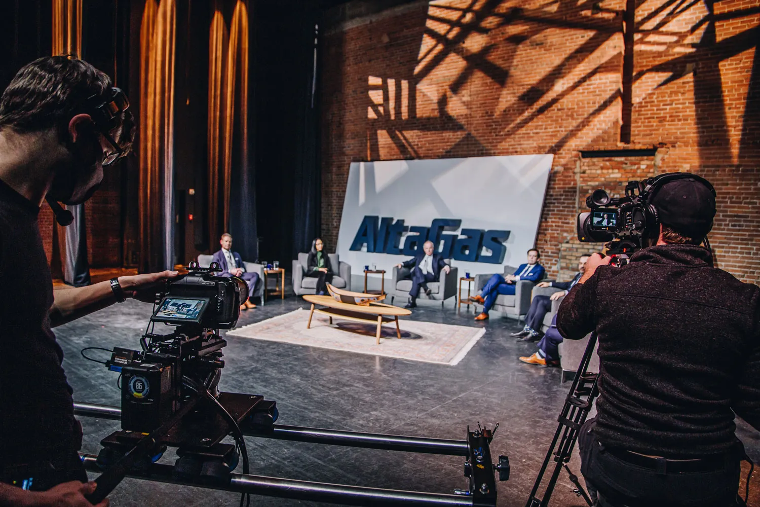 film crew using camera rigs to film the live event against a brick wall