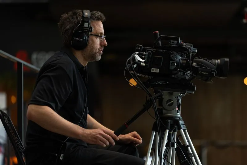 a camera man wearing headphones is working the camera on a tripod