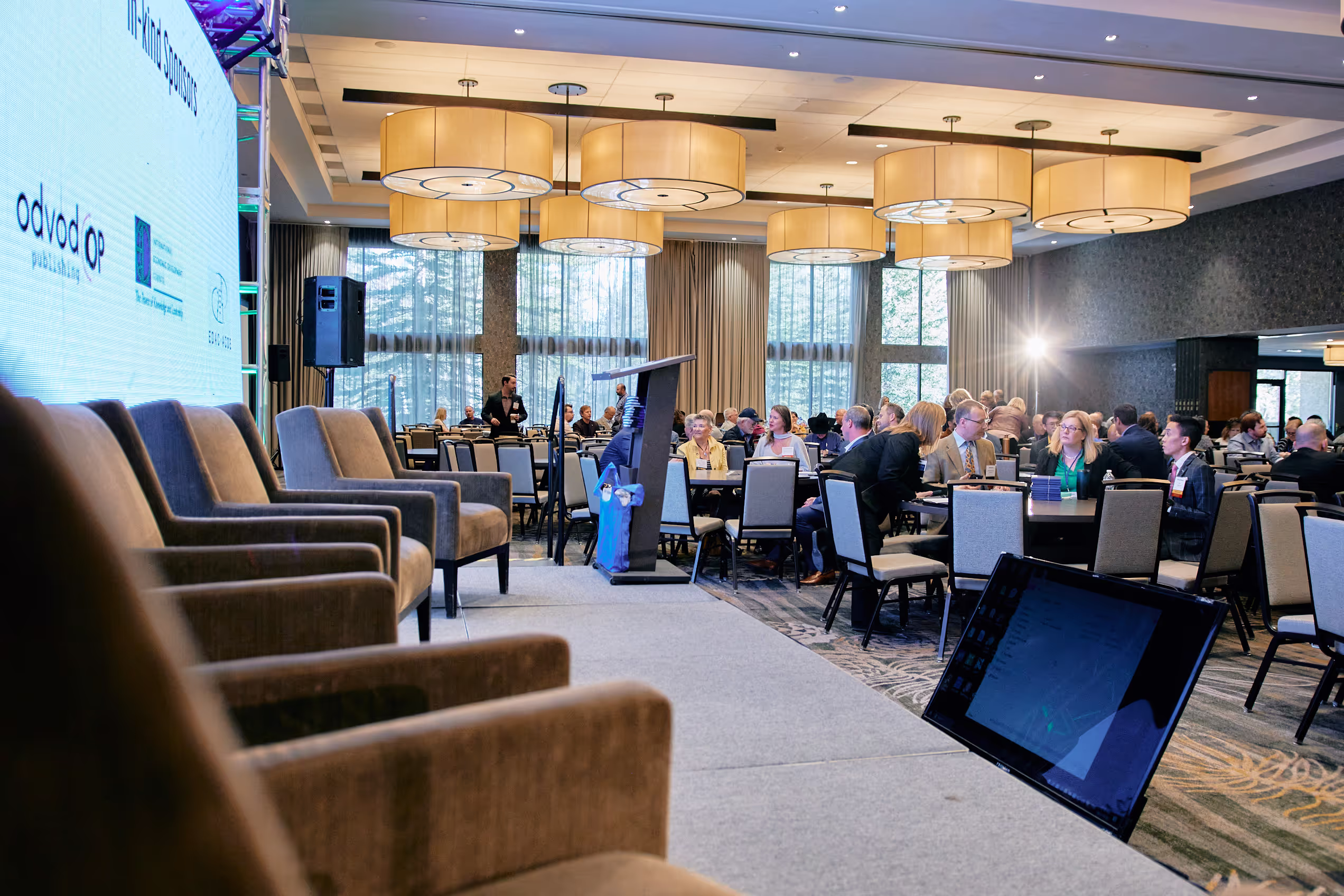 Professional stage setup at a conference, with attendees seated at tables, highlighting the agency's expertise in broadcast and AV services.