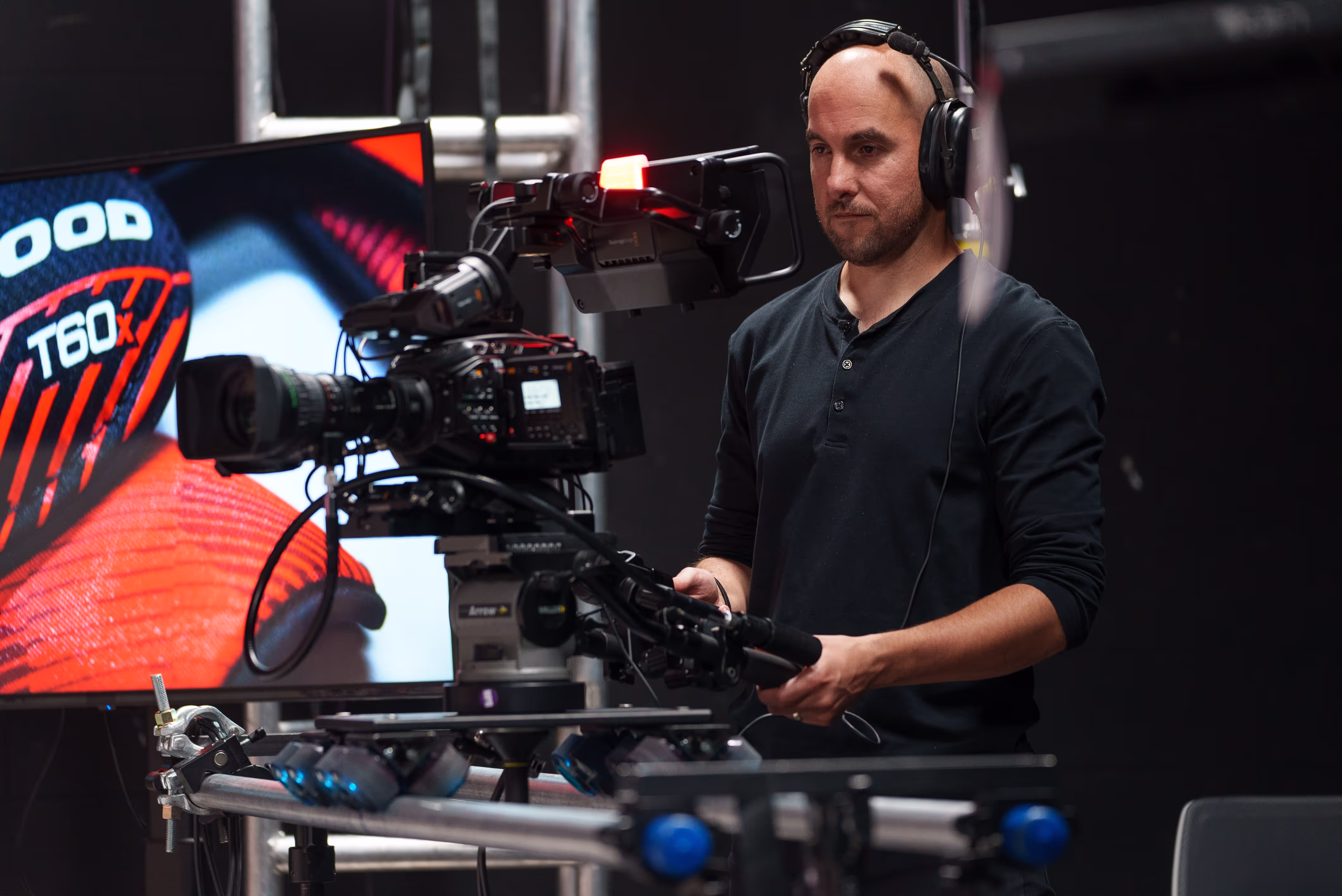 a camera man works the camera on a tripod wearing headphones