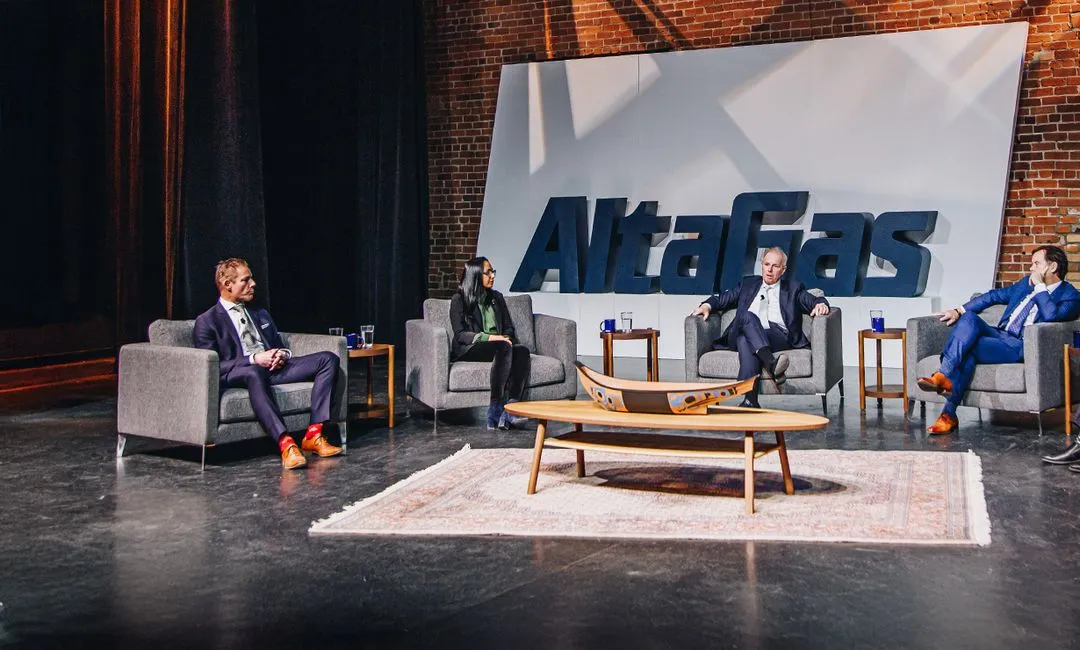 Four business professionals seated in gray armchairs on a stage with a large AltaGas sign behind them, engaged in a panel discussion.