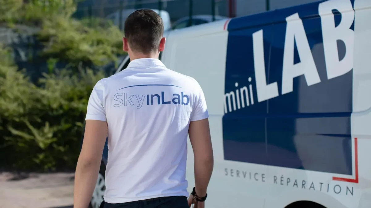 Technicien Sky'inLab devant le véhicule atelier miniLAB, service de réparation de menuiseries