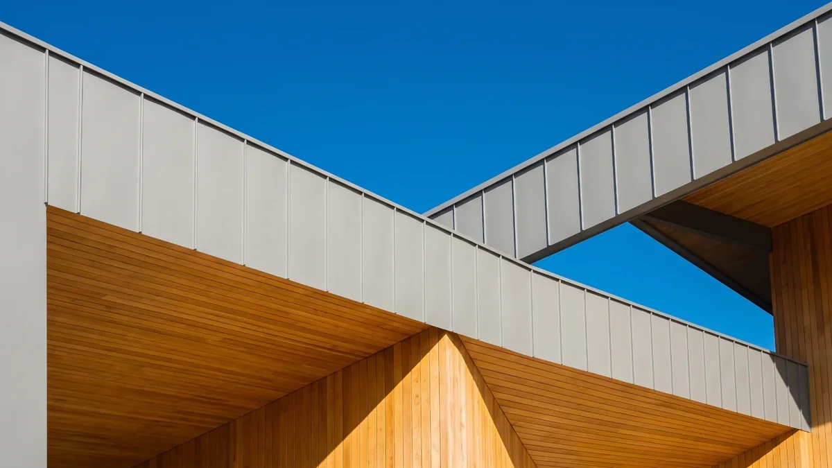 Toiture d'un bâtiment moderne en bardage métallique et bois, sous un ciel bleu