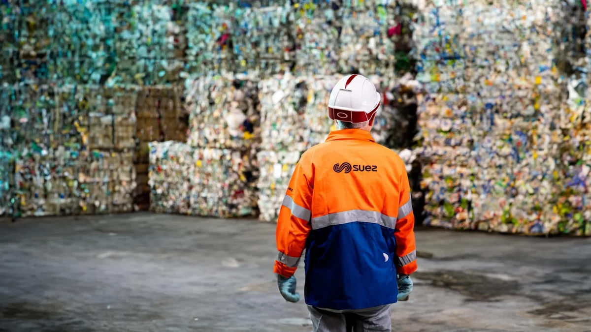 Collaborateur SUEZ en tenue de travail devant des balles de déchets triés
