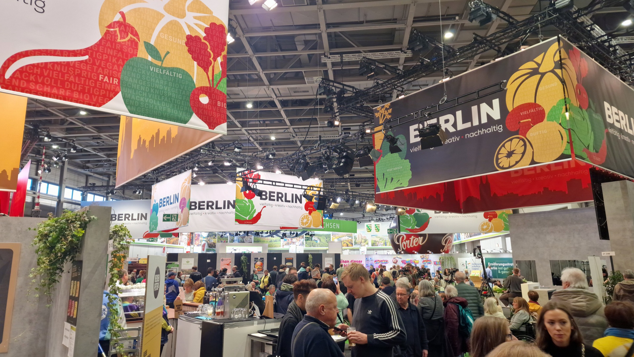 Crowded exhibition hall at Internationale Grüne Woche in Messe Berlin, with large Berlin banners overhead