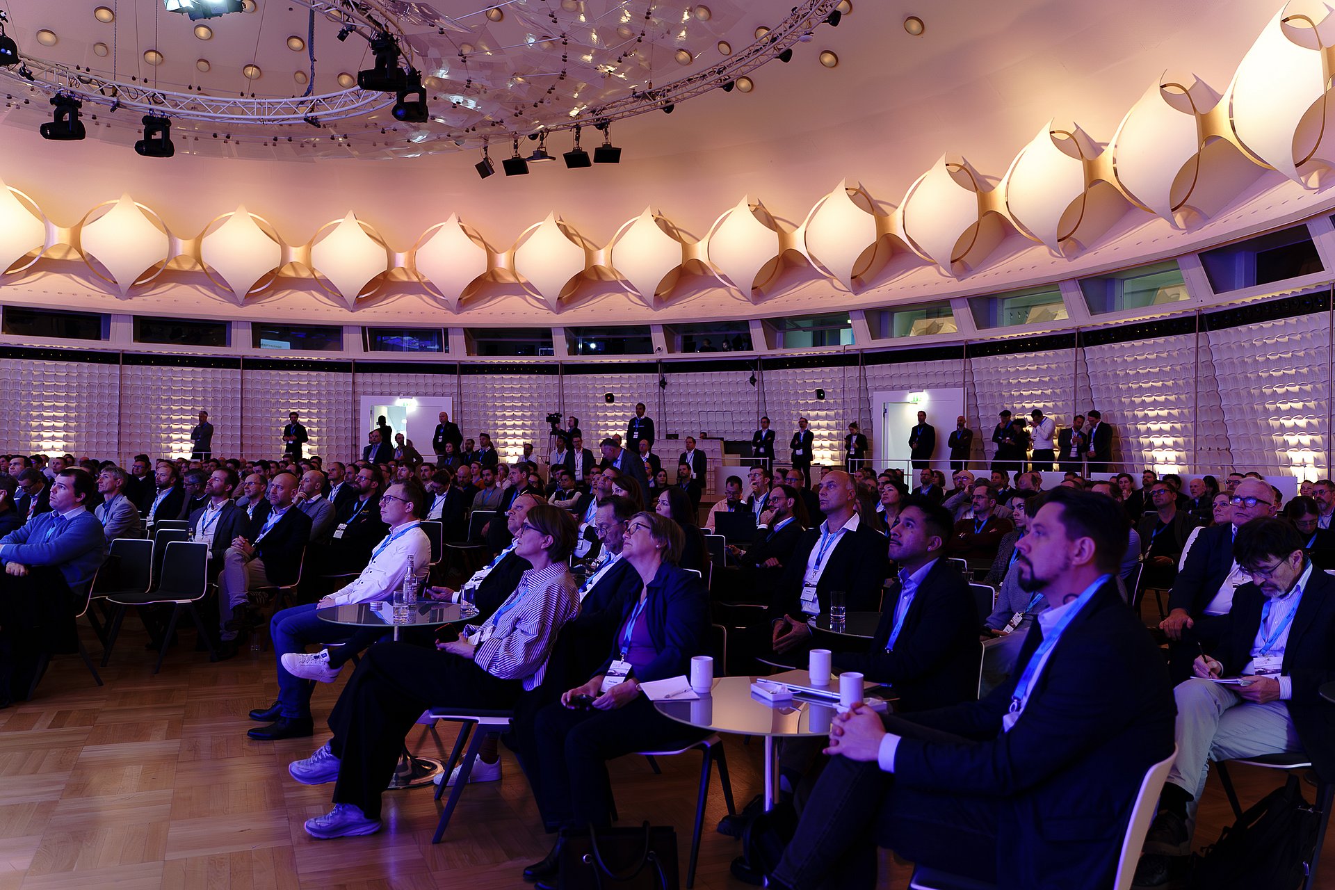 Audience filling the circular main hall of the bcc Berlin Congress Center at Forum Solar PLUS 2025, beneath its curved, illuminated ceiling.