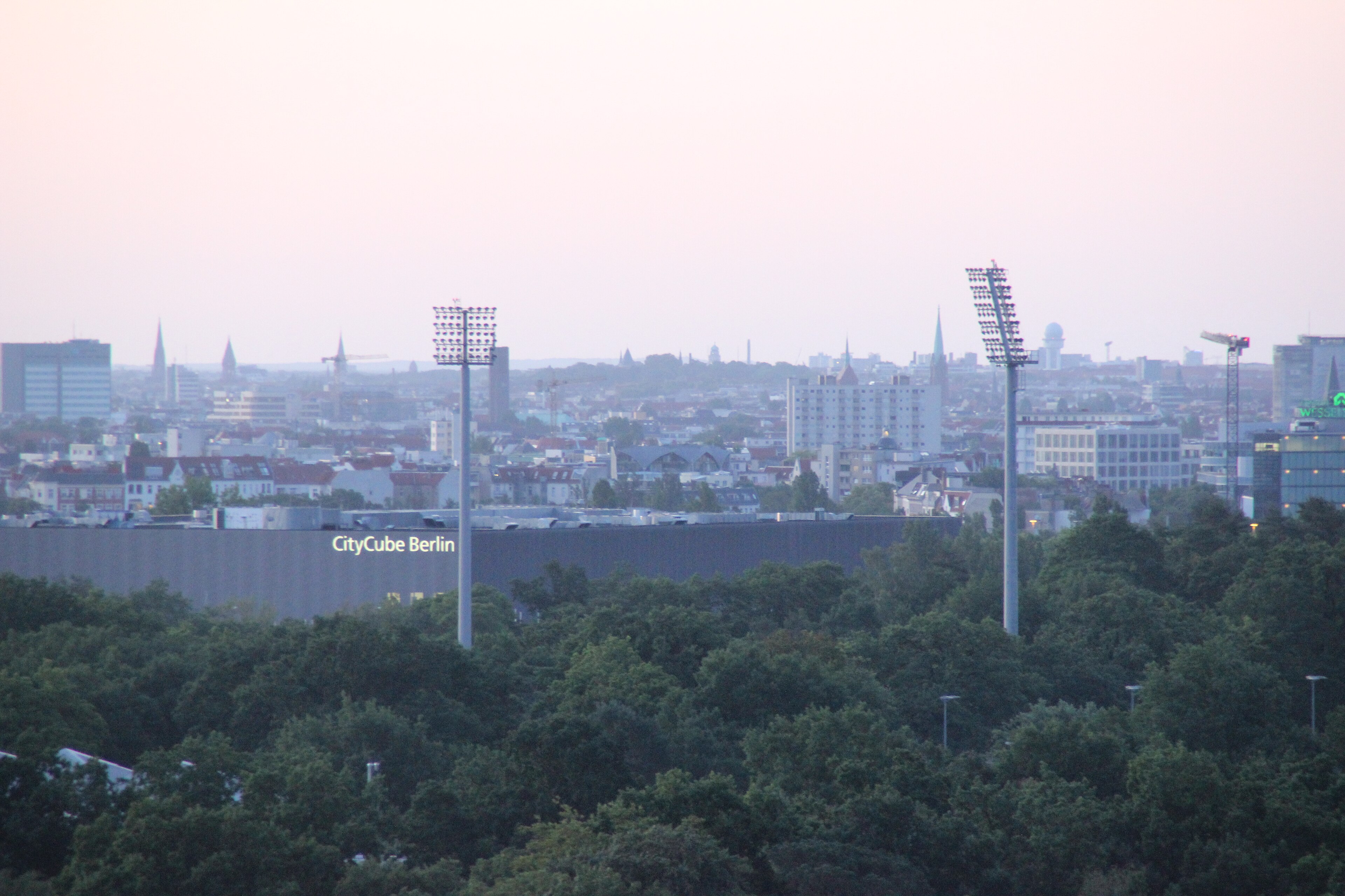 CityCube Berlin at dusk, seen across the trees of the Messe Berlin area