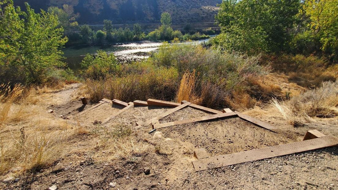 A completed wooden "post-assisted log structure" installed on a dry bank to stabilize soil and improve fish habitat near a flowing river.