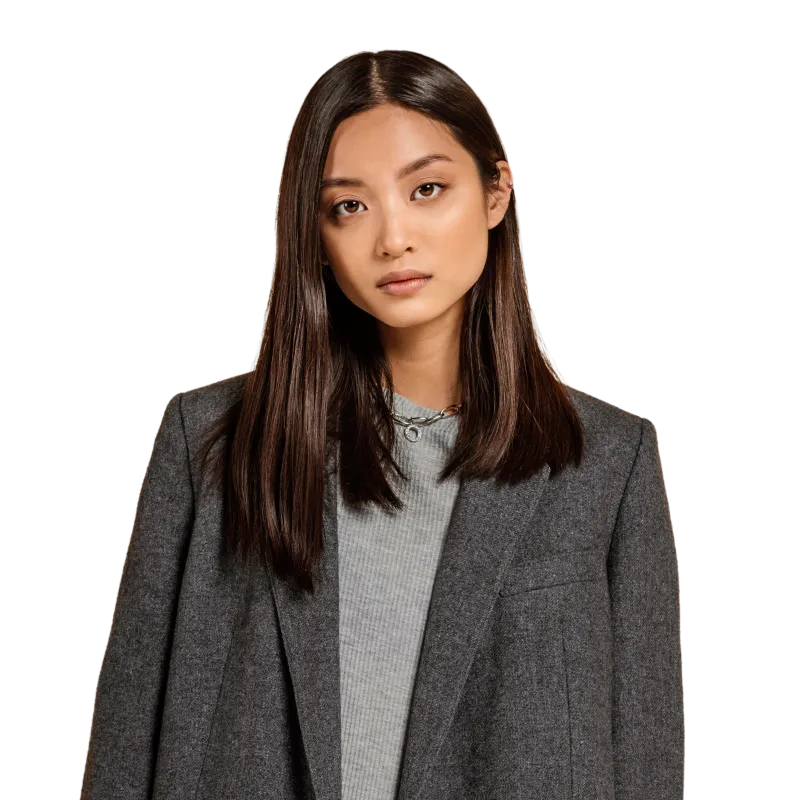 Young woman with straight dark hair wearing a grey blazer over a light grey top, looking directly at the camera.