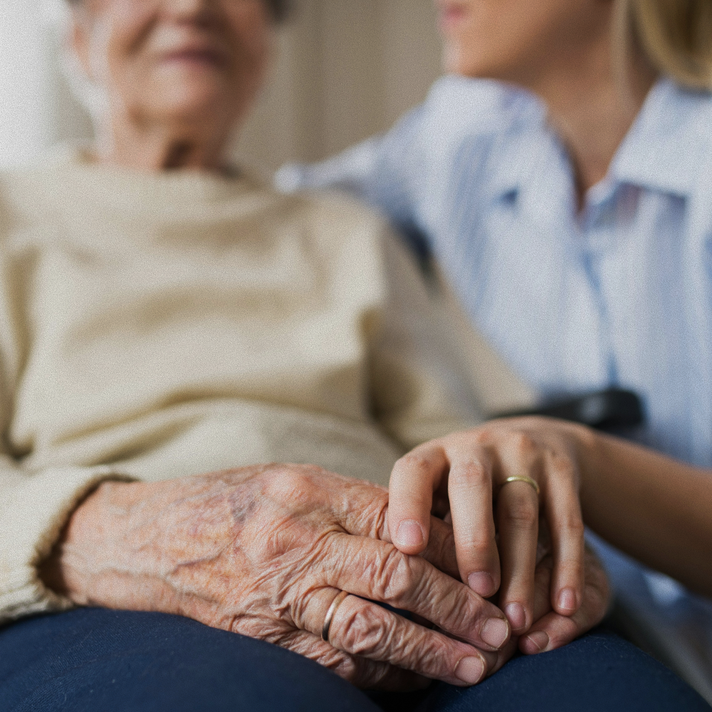 Close-up of a younger person gently holding an elderly person's hand, symbolizing care and support.