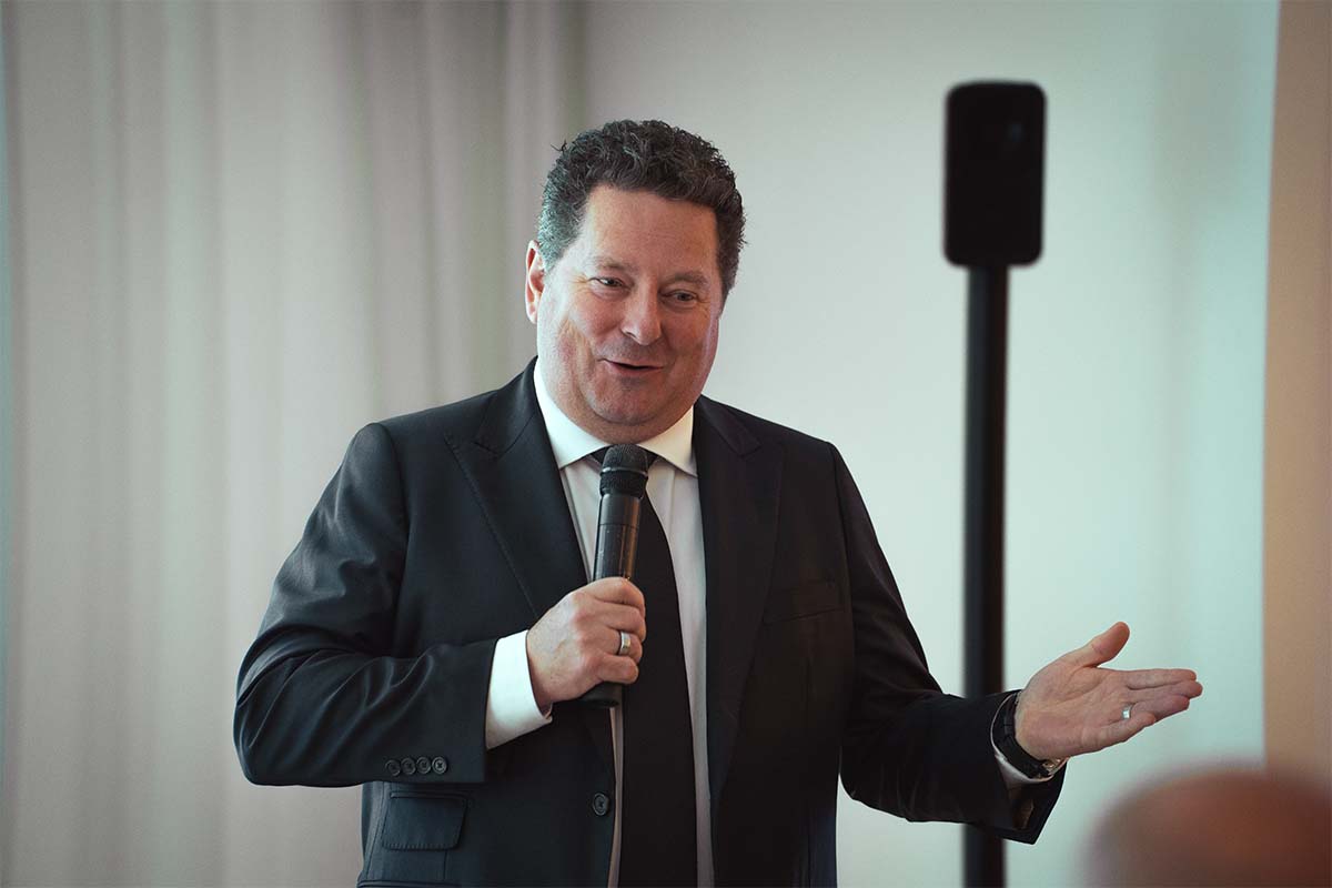 man giving a speech with microphone in hand at holiday gathering