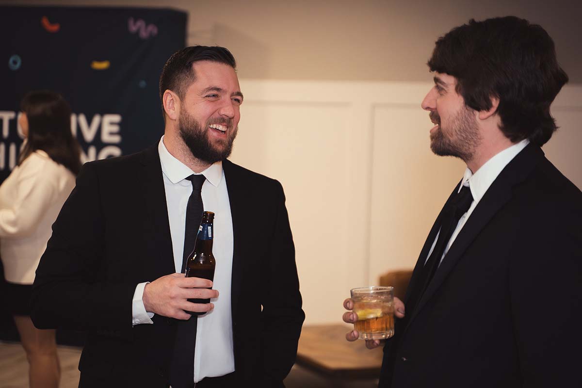 two men talking at holiday gathering dressed in suits