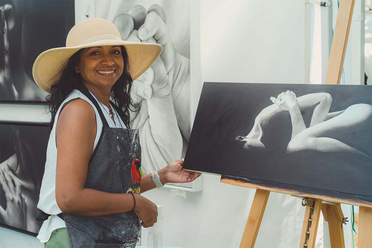 woman showcasing her painting on an easel
